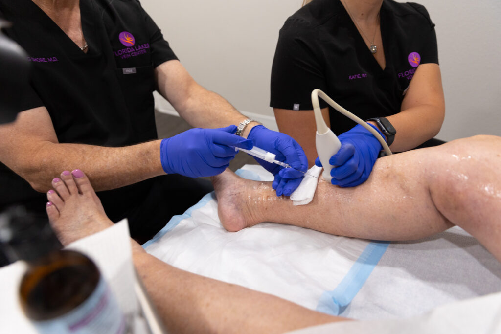 Two providers wear scrubs and medical gloves while they perform a varicose vein treatment near Longboat Key.