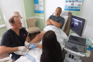 Two providers sit and examine an ultrasound during peripheral venous disease treatment in Lakewood Ranch.