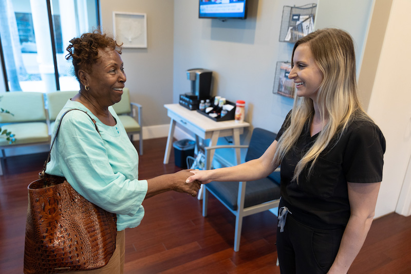Picture of a provider and a patient shaking hands in the lobby as she gets ready to improve circulation in Sarasota
