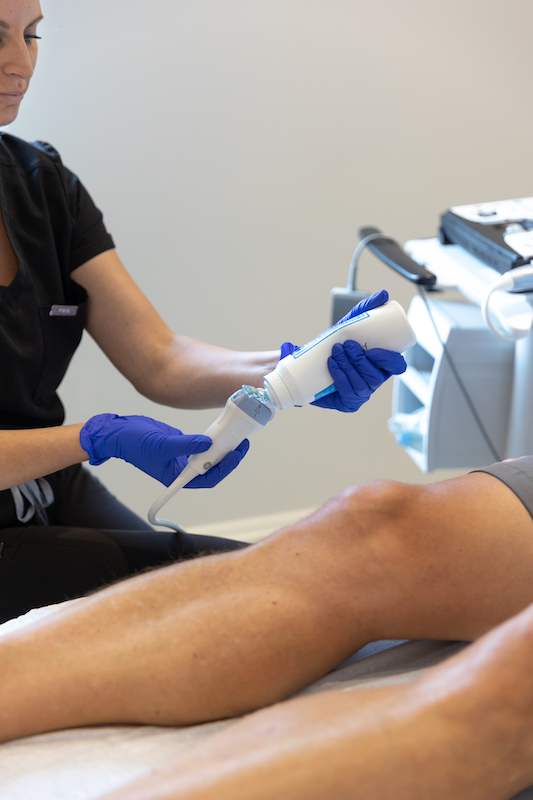 A health provider preparing an ultrasound scanner to put on the legs of at the bottom of the picture for DVT treatment in Sarasota